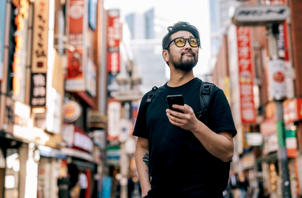 A traveler checking his phone on a busy Shibuya street in Tokyo